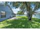 A view of the green backyard, patio, mature trees, and the exterior of the home at 1031 Seneca Trl, St Cloud, FL 34772