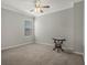 This carpeted bedroom is lit by a ceiling fan and features a window and antique side table at 1034 Huntspoint St, Winter Garden, FL 34787