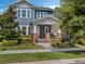 Blue two-story home with a welcoming front porch with brick pillars and steps and lush, manicured landscaping at 1034 Huntspoint St, Winter Garden, FL 34787