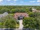 Stunning aerial view of a luxurious home with a tile roof surrounded by lush landscaping and mature trees at 10915 Emerald Chase Dr, Orlando, FL 32836