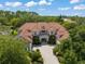 Expansive aerial view of a grand residence showcasing the tile roof, manicured grounds, and verdant surroundings at 10915 Emerald Chase Dr, Orlando, FL 32836