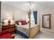 Cozy bedroom featuring floral bedding, natural light, and a wooden four-poster bed frame at 10915 Emerald Chase Dr, Orlando, FL 32836