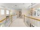 Bright hallway with white carpet, recessed lighting, chandelier, and wooden railing at 10915 Emerald Chase Dr, Orlando, FL 32836