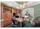 A handsome home office boasts custom wood built-ins, a tray ceiling, and a large window for natural light at 10915 Emerald Chase Dr, Orlando, FL 32836