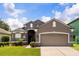 Beautiful exterior shot of a gray house with well-manicured landscaping and a two-car garage at 13658 Hidden Forest Cir, Orlando, FL 32828