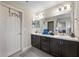 Bright bathroom with double sink vanity, sleek dark cabinets, and a large mirror at 220 Foxtail Loop, Davenport, FL 33837