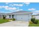 Beautiful home featuring a two-car garage and well-maintained landscaping under a bright, cloudy sky at 220 Foxtail Loop, Davenport, FL 33837