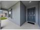 Covered porch with dark gray front door and gray siding, plus a view of manicured lawn at 220 Foxtail Loop, Davenport, FL 33837