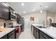Modern kitchen with dark cabinetry, stainless steel appliances, and a large island with marble countertops at 220 Foxtail Loop, Davenport, FL 33837