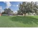 Wide backyard featuring a screened pool enclosure, mature trees, and green grass, offering ample space at 2800 Woodsmere Ct, Kissimmee, FL 34746