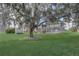 Expansive backyard featuring mature trees, a screened-in pool enclosure, and a well-manicured lawn at 2800 Woodsmere Ct, Kissimmee, FL 34746