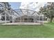 Spacious backyard featuring a screened pool enclosure, green lawn, and mature trees, offering privacy at 2800 Woodsmere Ct, Kissimmee, FL 34746