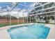 Screened-in pool with attached spa, blue tile accents, and brick privacy wall at 2800 Woodsmere Ct, Kissimmee, FL 34746