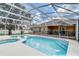 Backyard pool and spa with screened enclosure, patio, and well-manicured lawn and mature trees at 2800 Woodsmere Ct, Kissimmee, FL 34746