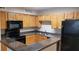 A kitchen with wood cabinets, dark grey countertops, and black appliances provides a functional cooking space at 420 Forestway Cir # 202, Altamonte Springs, FL 32701