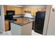 Cozy kitchen with wood cabinets, black appliances and breakfast bar with dark grey countertops at 420 Forestway Cir # 202, Altamonte Springs, FL 32701