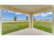 A covered patio with a view of the lawn and young trees on a sunny day at 5174 Masser Rd, St Cloud, FL 34772
