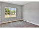 An empty bedroom with neutral carpet and gray walls, featuring a window with a green outdoor view at 6291 Sw 133Rd Street Road, Ocala, FL 34473