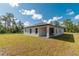Rear exterior view showing the home's roofline, windows, covered patio, and lush lawn at 6291 Sw 133Rd Street Road, Ocala, FL 34473