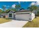 Bright home featuring white exterior, dark accents, a long driveway, and well-manicured lawn at 6291 Sw 133Rd Street Road, Ocala, FL 34473