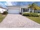 Long, brick paver driveway leading to a single-Gathering home with a two-car garage and tropical landscaping at 6300 Chirpine Ln, St Cloud, FL 34771