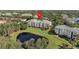 Aerial view of an inviting apartment complex next to a serene lake surrounded by lush greenery and mature trees at 8816 Dunes Ct # 303, Kissimmee, FL 34747