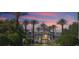 Exterior view of the clubhouse at sunset with lush landscaping, palm trees and patriotic flags at 8816 Dunes Ct # 303, Kissimmee, FL 34747