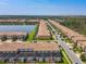 Aerial view of a community with tile roofed homes along a lake and lush landscaping at 8911 Geneve Ct, Kissimmee, FL 34747