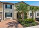 Inviting townhome featuring a red brick driveway, lush landscaping, and classic architectural details at 8911 Geneve Ct, Kissimmee, FL 34747