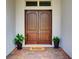 Inviting double front doors with a welcome mat and potted plants, creating a warm entrance to the home at 9979 Winnington St, Orlando, FL 32832