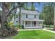 Inviting two-story home with a covered front porch, mature trees, and a well-manicured lawn creates a welcoming atmosphere at 1021 S Elm Ave, Sanford, FL 32771