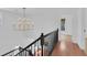 Hallway with black railing, hardwood floors, and a view of a gold chandelier at 1021 S Elm Ave, Sanford, FL 32771