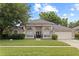 Charming single-story home with arched windows, lush lawn, mature trees, and a welcoming double-door entrance at 1103 Lake Legro Ct, Orlando, FL 32835