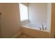 A relaxing soaking bathtub next to a window providing natural light and an elegant faucet at 1105 Citrus Landings Blvd, Davenport, FL 33837