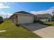 Side view of a single-Gathering home showcasing the driveway and two-car garage at 1105 Citrus Landings Blvd, Davenport, FL 33837