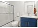 A modern bathroom featuring stylish, blue vanity, quartz countertops, and sliding shower doors at 12347 Ne 52Nd Loop, Oxford, FL 34484