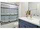 A modern bathroom featuring stylish, blue vanity, quartz countertops, and decorative shower curtains at 12347 Ne 52Nd Loop, Oxford, FL 34484