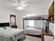 A simple bedroom featuring two beds, wood floors, neutral walls, and a ceiling fan at 12347 Ne 52Nd Loop, Oxford, FL 34484