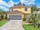 Inviting two-story home featuring a well-manicured lawn, grey garage door, and lush landscaping at 12347 Ne 52Nd Loop, Oxford, FL 34484