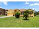 Charming yellow home featuring a lush green lawn, landscaped front yard, and two-car garage at 1457 Teal Dr, Kissimmee, FL 34759