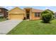 Inviting front yard of a yellow home with well-kept lawn and a two-car garage at 1457 Teal Dr, Kissimmee, FL 34759