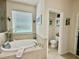 Well-lit bathroom features a soaking tub with tile surround and separate toilet room at 1573 Amber Leaf Cir, Ocoee, FL 34761