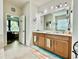 Bright bathroom with double vanity, wood cabinets, and a door leading to main bedroom at 1573 Amber Leaf Cir, Ocoee, FL 34761