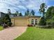 Charming single-story home with a brick driveway, well-manicured lawn, and lush landscaping at 1573 Amber Leaf Cir, Ocoee, FL 34761