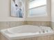 Close-up of a relaxing soaking tub with tile surround, and chrome hardware in a bright bathroom at 2009 E Grant St, Orlando, FL 32806