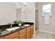 Bathroom featuring double sinks, black granite countertop, wood cabinets, and tile flooring in a neutral color palette at 2009 E Grant St, Orlando, FL 32806