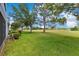 The backyard features a large grassy space, mature trees, and landscaping bordering the community at 20610 Maxim Pkwy, Orlando, FL 32833
