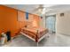 Bright bedroom with orange accent wall, decorative wall hangings, white metal frame bed, and tiled flooring at 2309 Cilantro Dr, Orlando, FL 32837