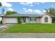 Charming single-story home with a well-maintained lawn and attached garage, features a whimsical pink and teal exterior at 2309 Cilantro Dr, Orlando, FL 32837