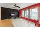 Tile-floored living area with a black accent wall, a mounted television, and bright red walls, lit by a modern ceiling fan at 2309 Cilantro Dr, Orlando, FL 32837